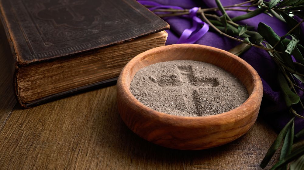 bowl of sand with cross image next to Bible