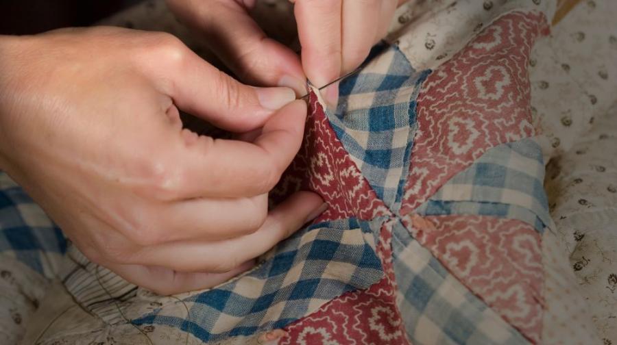 hands tying a quilt
