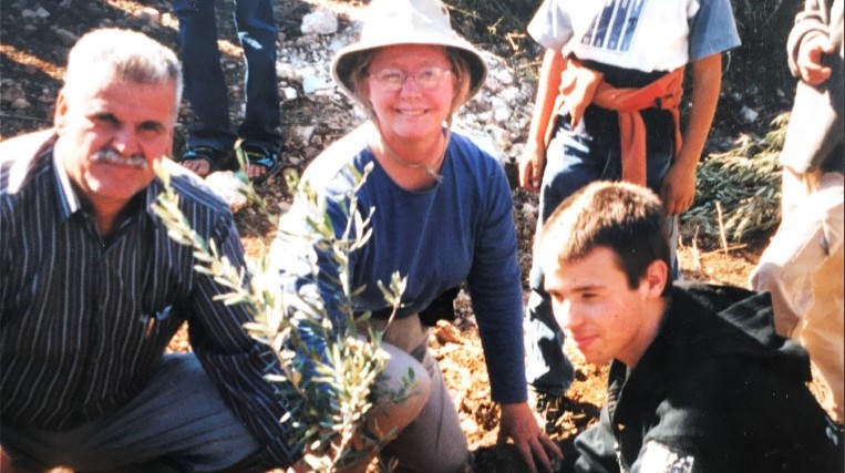 A Palestinian, a Northfielder, and an Israeli planting an olive tree in Palestine.