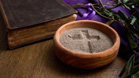 bowl of sand with cross image next to Bible